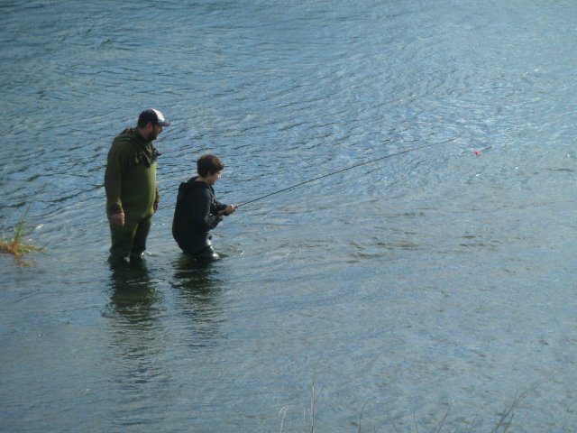 Boy playing a fish guided by his dad